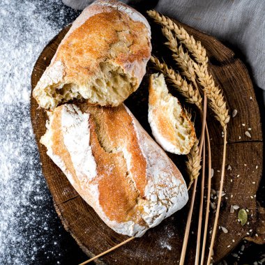 Unun yanında yuvarlak bir tahtada duran beyaz undan yapılmış taze taze ev yapımı ekmek.