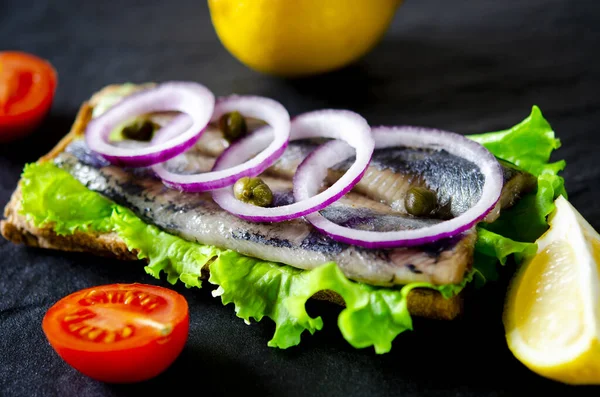 Tuz, biber, otlar, soğan ve beyaz arka plan üzerinde siyah plaka üzerinde limon ile ringa balığı filetosu. Üstten Görünüm. sağlıklı gıda