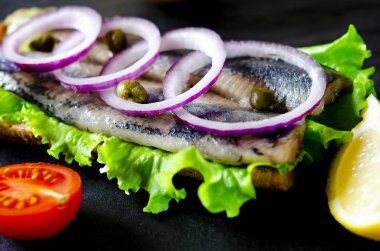 Tuz, biber, otlar, soğan ve beyaz arka plan üzerinde siyah plaka üzerinde limon ile ringa balığı filetosu. Üstten Görünüm. sağlıklı gıda