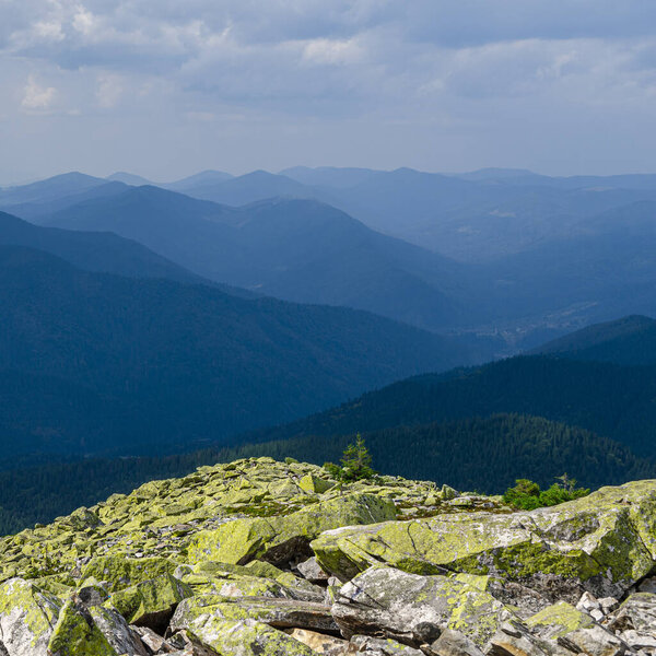 Extreme mountain hikes. Huge stones overgrown with green ome stoch against the backdrop of high mountain ranges in the fog
