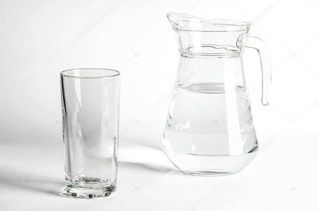 Pure clear water in a glass and jug stands on a white background. isolated