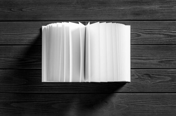 A white book with white pages lies on a black wooden background. Close-up