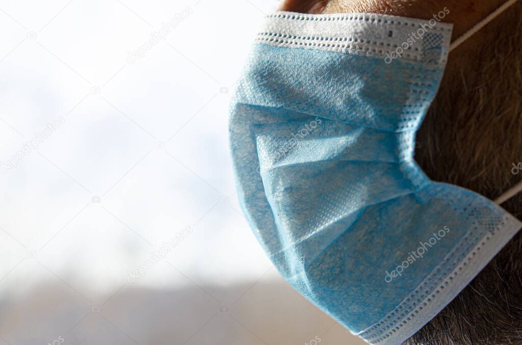 The face of a man in a blue protective medical mask. Close-up