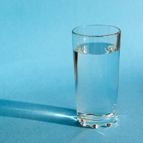 Egy Tiszta Tiszta Tiszta Vízzel Teli Pohár Áll Kék Háttérben — Stock Fotó
