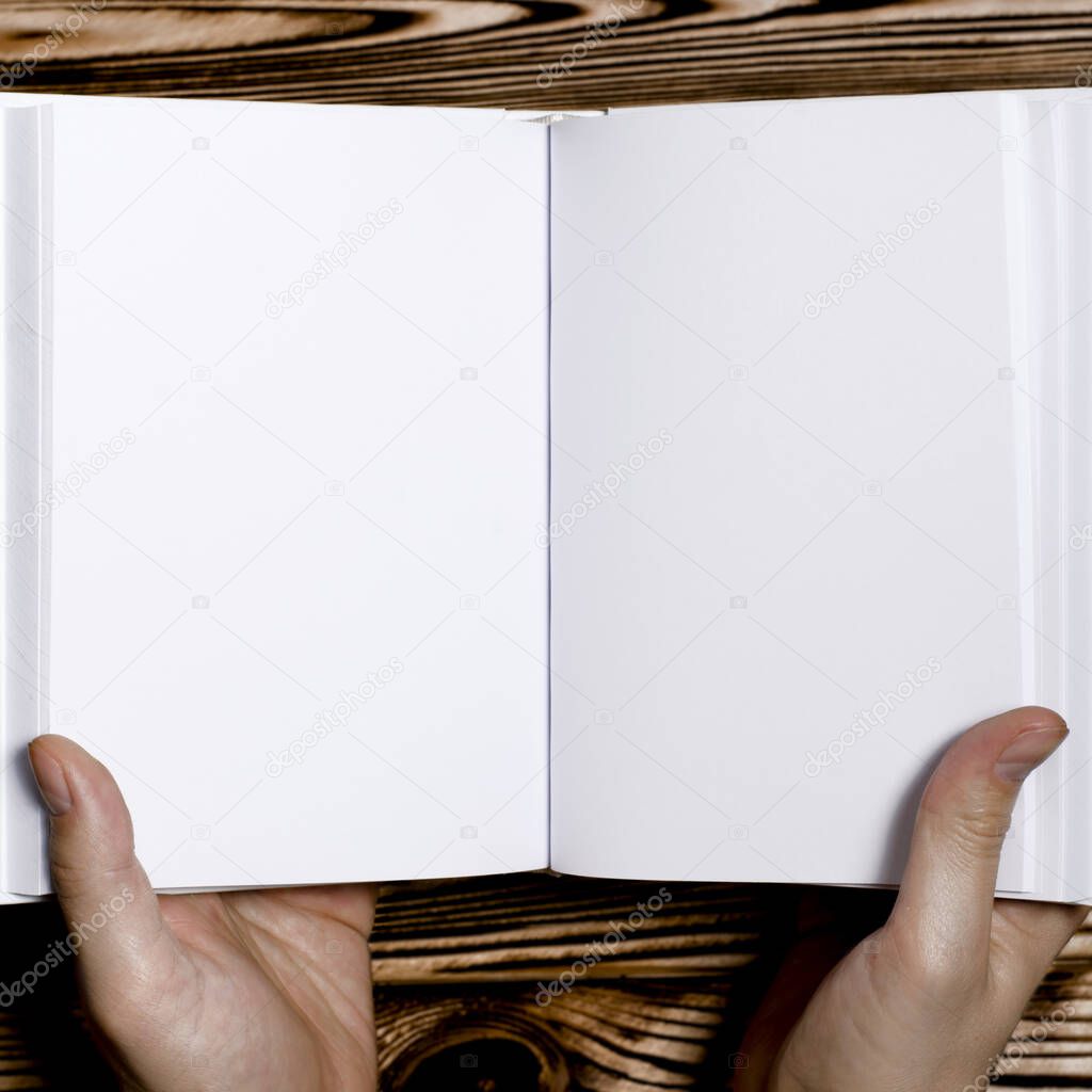 Men's hands holding open book with blank cover on light background. Mockup of open blank square book