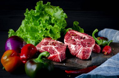 Et konsepti. Et biftekleri masada sebzelerle pişirmeye hazır. Yakın plan.