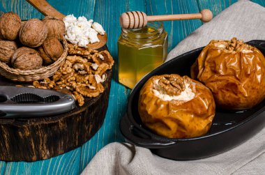 Sağlıklı beslenme. Kır peyniri, bal ve fındık ile pişirilmiş elmalar ahşap bir masada duruyor.