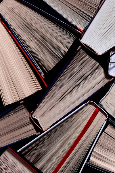 여러 가지 색깔의 열린 책들 이 오래 된 둥근 유리잔 옆 선반 위에 놓여 있다 — 스톡 사진