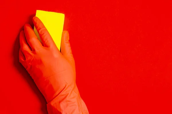 Żółty dom mycie gąbki w dłoni w czerwonej gumowej rękawicy na czerwonym tle — Zdjęcie stockowe