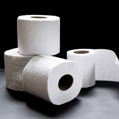 Siyah arka planda beyaz tuvalet kağıdı ruloları var. Yakın plan.