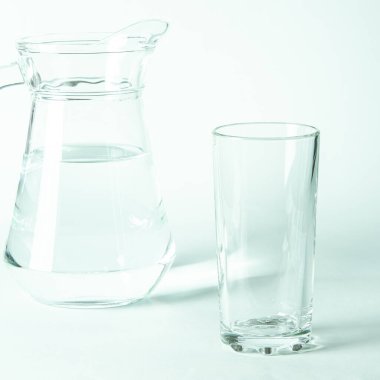 Bardaktaki saf temiz su ve sürahi beyaz arka planda duruyor. izole
