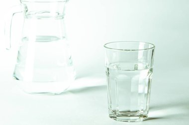Bardaktaki saf temiz su ve sürahi beyaz arka planda duruyor. izole