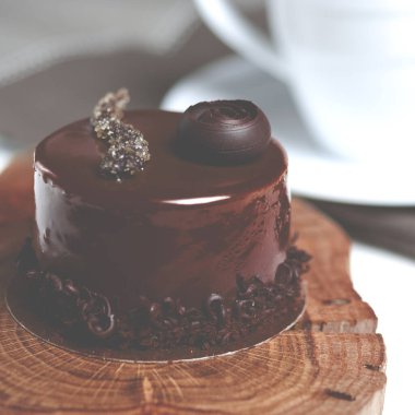 Çikolatalı tatlı. Çikolatalı kek dekoratif ahşap bir tabakta beyaz bir fincan kahvenin yanında duruyor.
