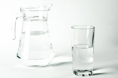 Bardaktaki saf temiz su ve sürahi beyaz arka planda duruyor. izole