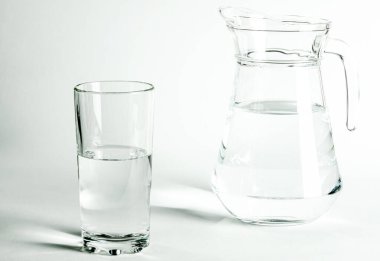 Bardaktaki saf temiz su ve sürahi beyaz arka planda duruyor. izole