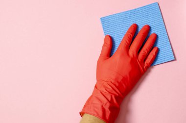 Mavi ev temizleme süngeri elinde pembe arka planda kırmızı lastik eldiven. Ticari temizlik şirketi konsepti