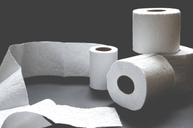 Siyah arka planda beyaz tuvalet kağıdı ruloları var. Yakın plan.