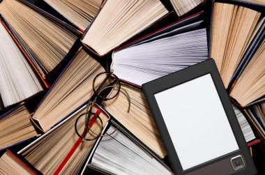 The e-book with a white screen lies on the open multi-colored books that lie on a dark background, ready to read. close-up clipart