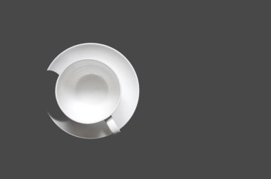 Siyah arka planda, tabakta siyah bisküviler olan beyaz bir fincan kahve duruyor. Üst görünüm