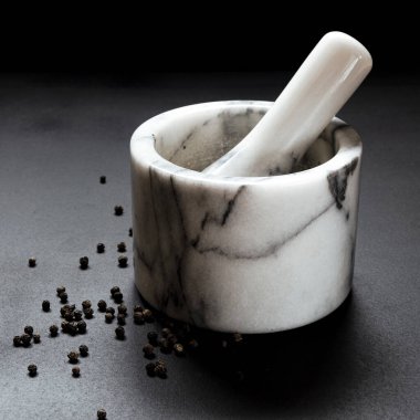 Biber öğütmek için kullanılan mermer havan topu siyah arka planda duruyor. Yakın plan.