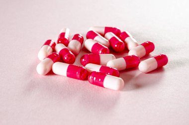 Beyaz oval kalp şeklinde tabletler pembe arka planda yatıyor. İlaç.