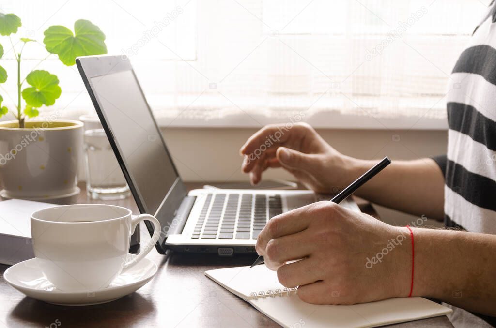 Freelancer works in the home office sitting at the desk near the window. Open laptop with blank screen on a white background top view