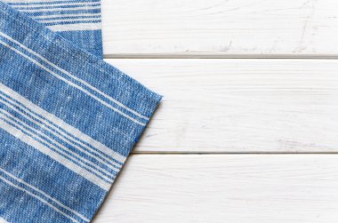 Beyaz çizgili mavi bir peçete beyaz ahşap bir masanın üzerinde duruyor. Yakın plan.
