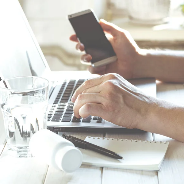 Freelancer merkez ofiste çalışıyor. Pencerenin yanındaki masada oturuyor. Beyaz arkaplan görünümünde boş ekran ile laptop aç