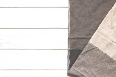 Çok renkli bir bez peçete beyaz ahşap bir arka planda duruyor. Üst görünüm