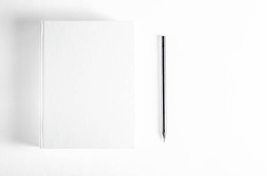 Mockup of closed blank square book and black pencil at white textured paper background. Hardcover Book Mock-Up - Dust Jacket. Wall Background
