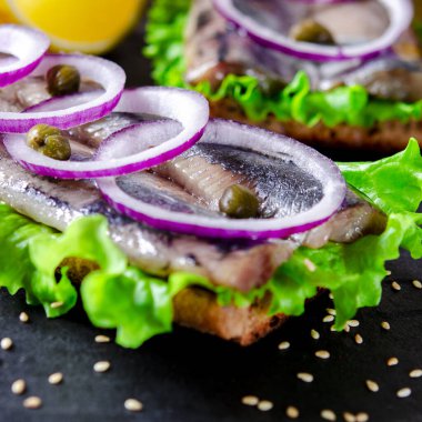 Tuz, biber, otlar, soğan ve beyaz arka plan üzerinde siyah plaka üzerinde limon ile ringa balığı filetosu. Üstten Görünüm. sağlıklı gıda