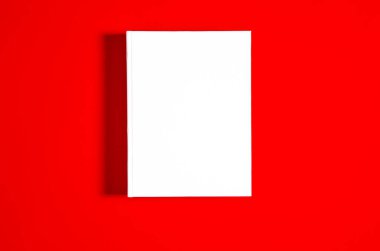 Beyaz desenli kağıt arkaplanda kapalı kare kitabın bir kopyası. Parlak kırmızı arkaplanda boş kare kapak şablonu