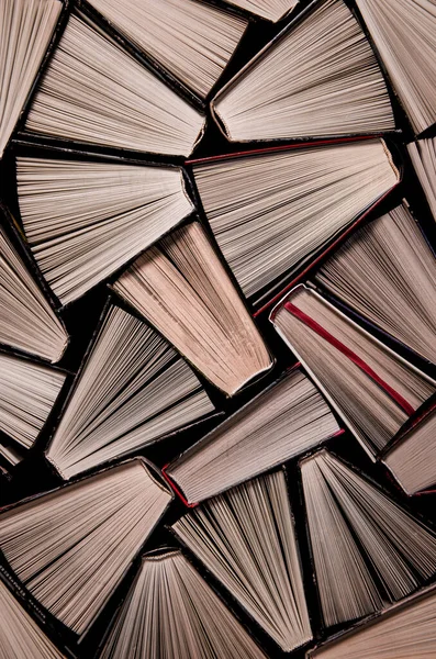 Kitaplar. Bir kitapçıda ya da kütüphanede birçok eski kitap var. Birçok renkli, kalın, karanlık arka planda duran kitap var. Okumaya hazır