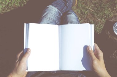 Elinde beyaz bir not defteri olan kot pantolonlu bir adam açık hava koltuğunda oturuyor. Serbest Çalışan