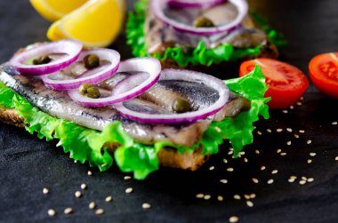 Tuz, biber, otlar, soğan ve beyaz arka plan üzerinde siyah plaka üzerinde limon ile ringa balığı filetosu. Üstten Görünüm. sağlıklı gıda