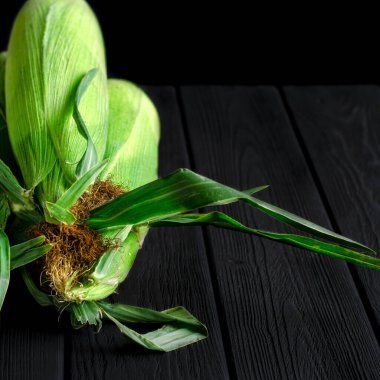 Yeşil yapraklı genç mısırların hasadı ahşap bir masada yatıyor. Yakın plan.