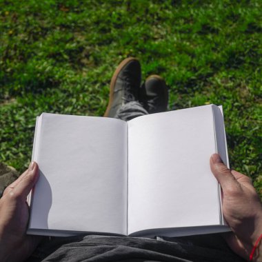Bahçede kendini izole etmiş bir adamın elindeki beyaz bir kitabın maketi gibi. Yakın plan.