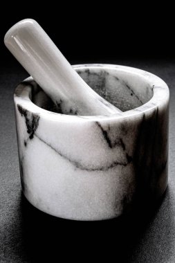 Biber öğütmek için kullanılan mermer havan topu siyah arka planda duruyor. Yakın plan.