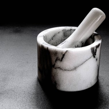 Biber öğütmek için kullanılan mermer havan topu siyah arka planda duruyor. Yakın plan.