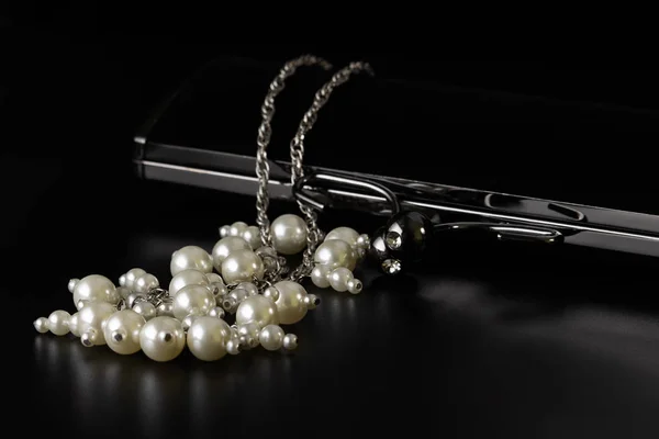 Abalorios de perlas con un embrague de terciopelo negro sobre la mesa . — Foto de Stock