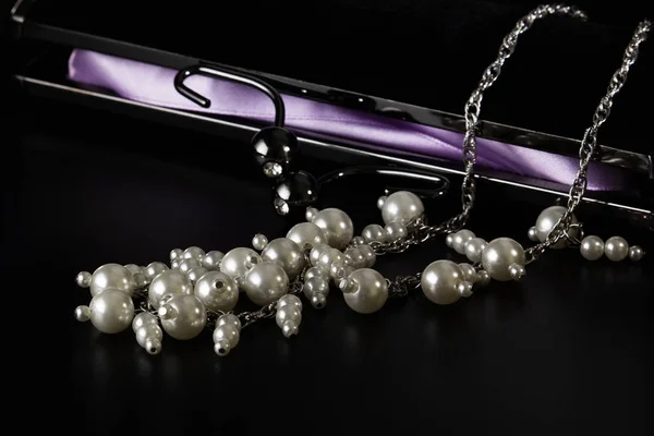 Abalorios de perlas con un embrague de terciopelo negro sobre la mesa . — Foto de Stock
