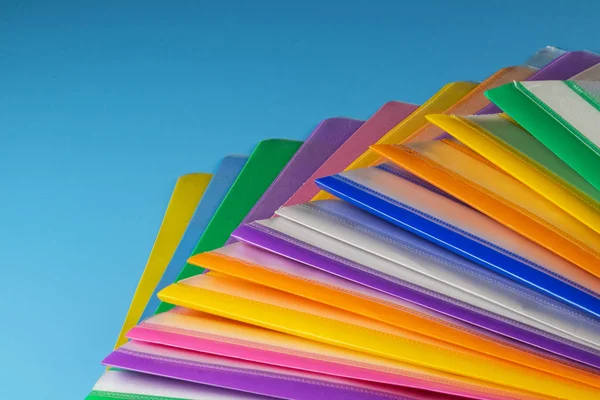 Mavi arkaplandaki kağıt için çok renkli plastik klasörler.