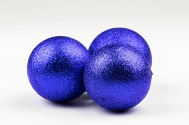 Beyaz arka planda üç mavi noel topu.