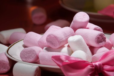 Bir tabağa beyaz ve pembe şekerlemeler serpiştirilmiş. 