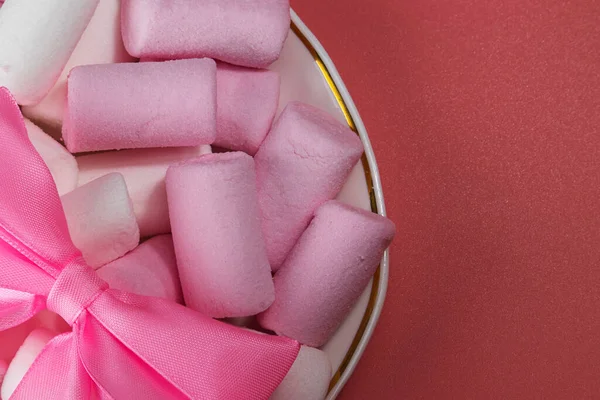 Marshmallows-Bonbons mit rosa Schleife auf Untertasse. — Stockfoto