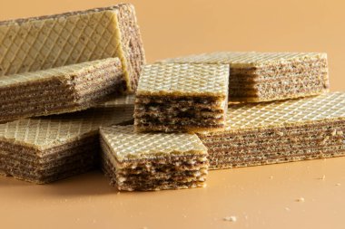Kahverengi dolgulu birkaç parça gevrek gofret bej arkaplanlı bir masada yatıyor..