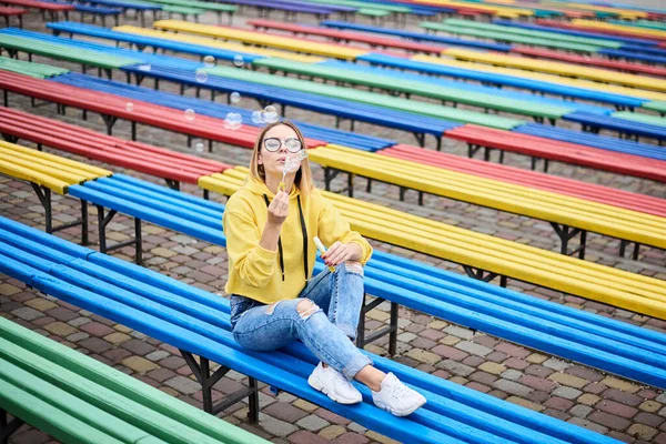 Jovem Loira Usando Capuz Amarelo Jeans Azuis Óculos Sentada Banco — Fotografia de Stock