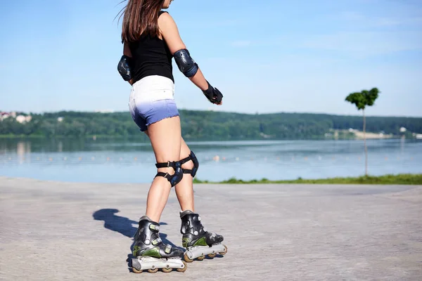 年轻的女人 滚轮跑道上的滚轮 陈氏腿 穿着轮滑鞋和防护设备 展示了骑在金属平台上的过程 — 图库照片