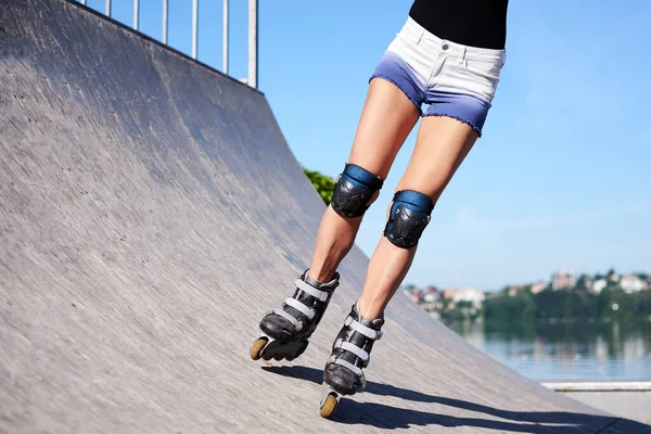 年轻的女人 滚轮跑道上的滚轮 陈氏腿 穿着轮滑鞋和防护设备 展示了骑在金属平台上的过程 — 图库照片