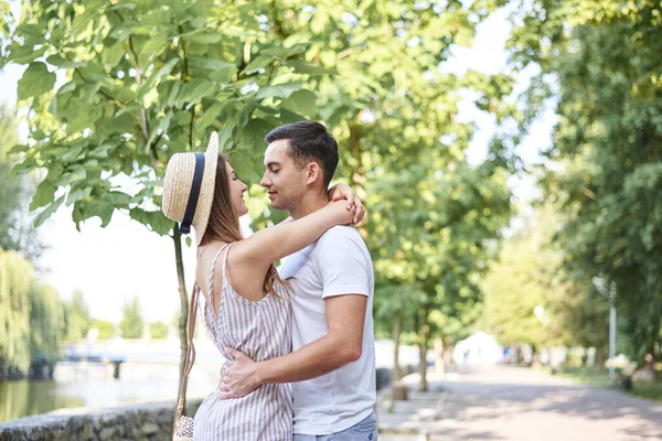 年轻夫妇恋爱了 夏天拥抱在公园里 漂亮的金发女孩全身条纹和草帽浪漫的约会与英俊的黑发家伙在白色的T恤 星期日城市步行 — 图库照片